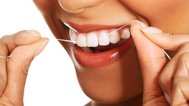 Žena si čistí zuby dentální nití